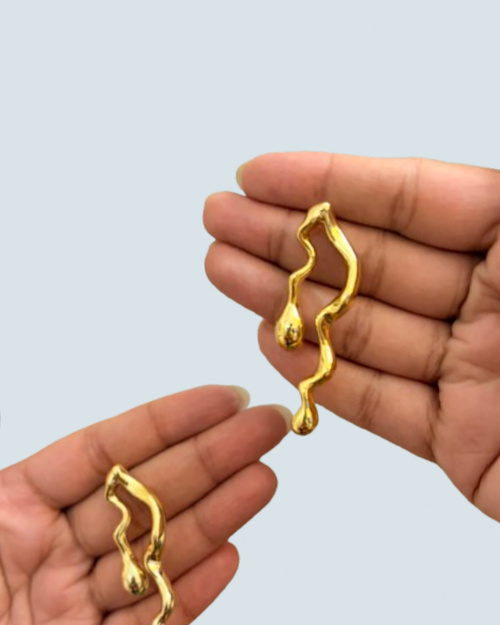 Premium golden drift gold-tone dangle earrings displayed in hand - Trinketly BD