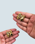 Small bow bloom gold-tone stud earrings shown in hand - Trinketly BD