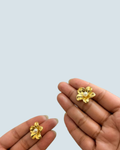 Dainty pearl blossom gold-tone studs shown in hand for size reference - Trinketly BD