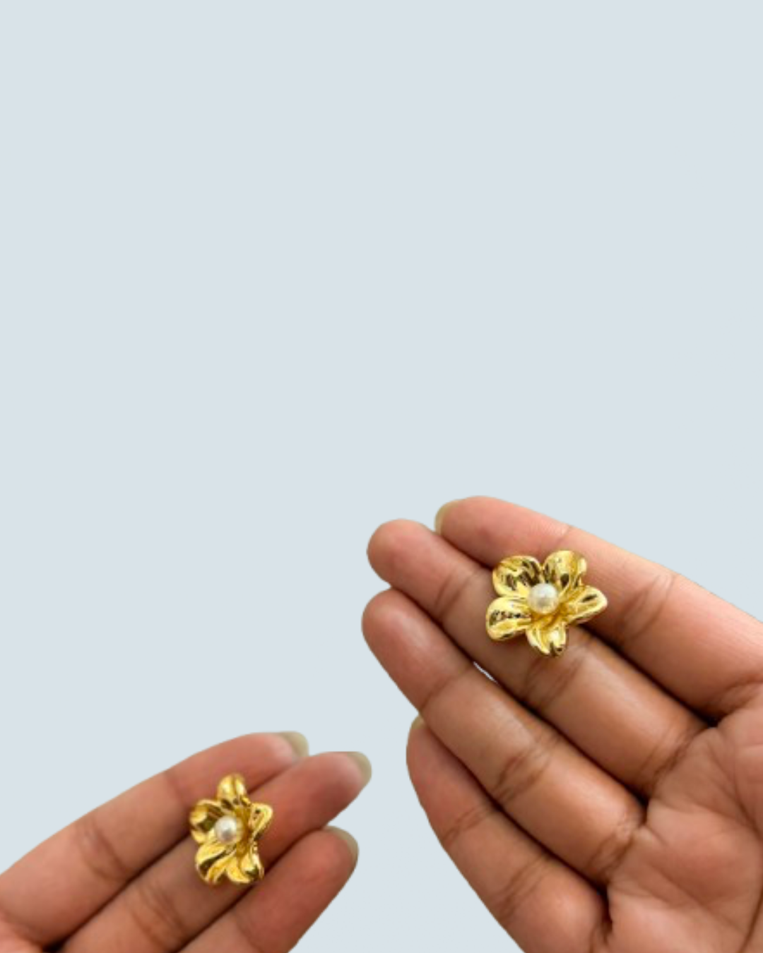 Dainty pearl blossom gold-tone studs shown in hand for size reference - Trinketly BD