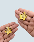 Small petal bloom gold-tone stud earrings held between fingers - Trinketly BD